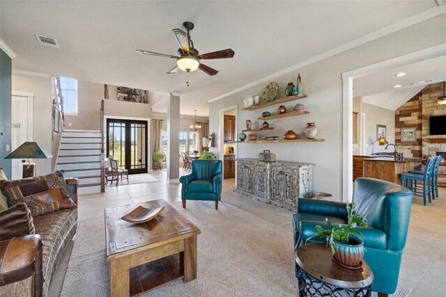 living room with light tile patterned flooring, stairway, a ceiling fan, visible vents, and ornamental molding