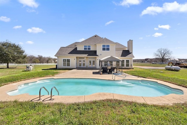 outdoor pool featuring french doors, a patio, and a lawn