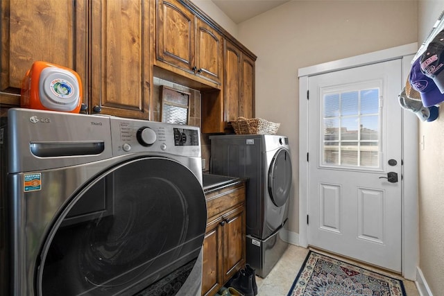 clothes washing area featuring independent washer and dryer, cabinet space, and baseboards