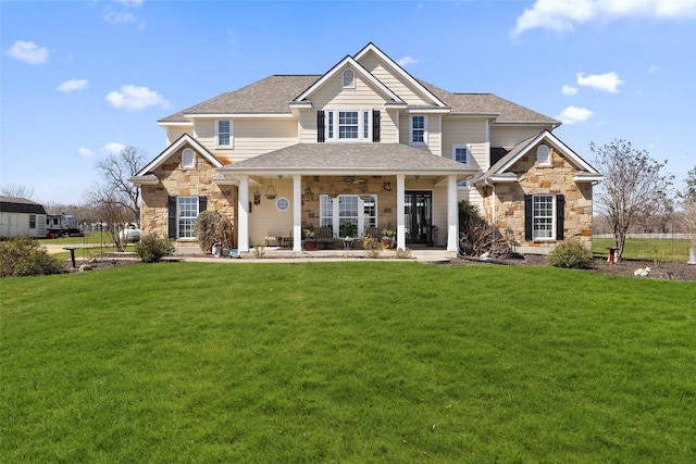 rear view of property featuring stone siding, a shingled roof, and a lawn