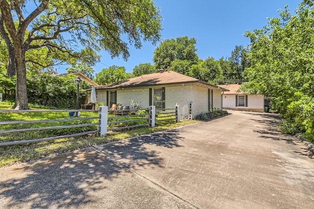 ranch-style home featuring a fenced front yard, concrete driveway, and brick siding