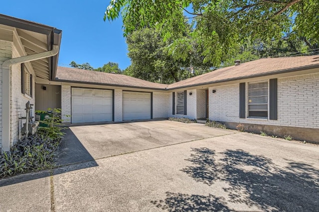 view of front of house featuring an attached garage, concrete driveway, and brick siding