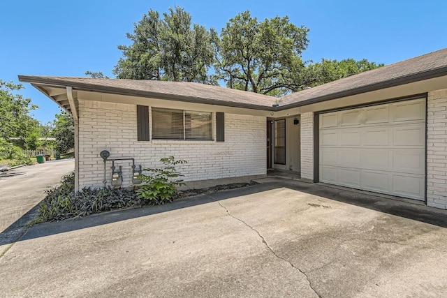 ranch-style home with a garage, brick siding, and driveway