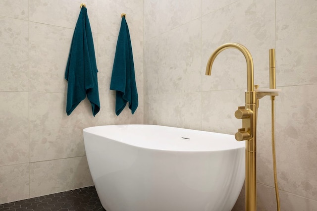 bathroom with a freestanding tub, tile walls, and tile patterned floors