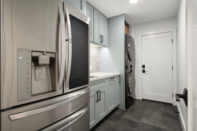 kitchen with stacked washing maching and dryer, light countertops, backsplash, and stainless steel fridge with ice dispenser