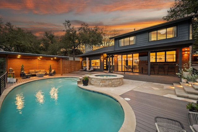 pool at dusk with an outdoor hangout area, an in ground hot tub, a patio, and a fenced in pool