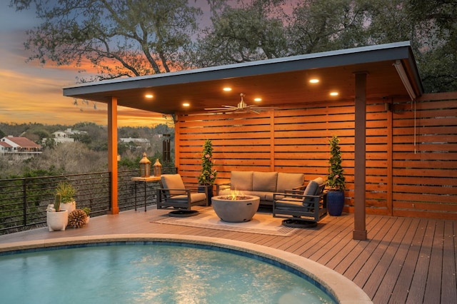 pool at dusk featuring a fenced in pool, an outdoor living space with a fire pit, and a deck