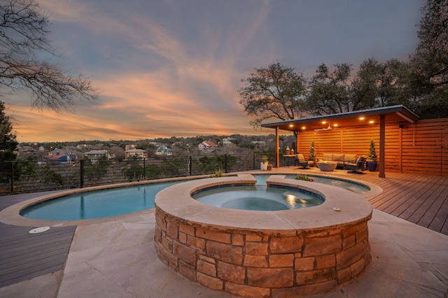 view of pool featuring a fenced in pool, an in ground hot tub, fence, a deck, and an outdoor living space