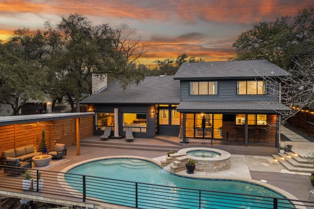 rear view of house with a chimney, an outdoor pool, a deck, and an in ground hot tub