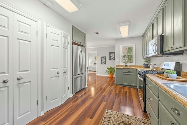 kitchen featuring visible vents, dark wood-type flooring, stainless steel appliances, light countertops, and green cabinets