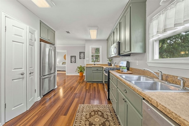 kitchen with dark wood finished floors, visible vents, green cabinets, appliances with stainless steel finishes, and a sink