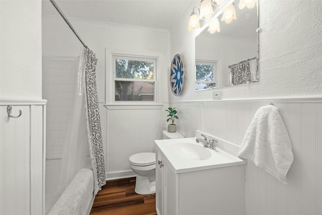 bathroom with toilet, a wainscoted wall, wood finished floors, vanity, and crown molding