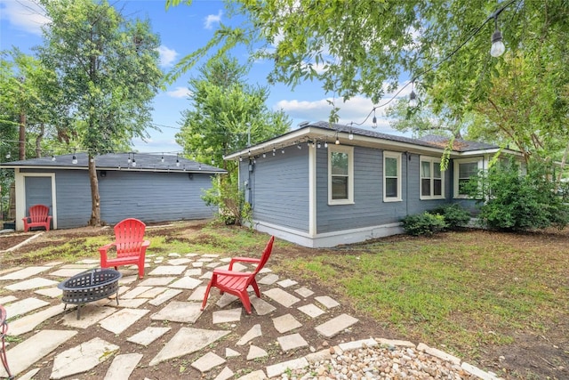 back of property with a patio area, a yard, and a fire pit