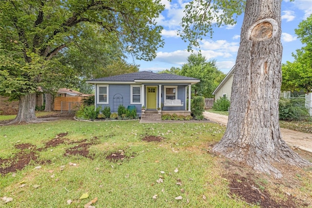 bungalow-style home with a porch, a front yard, and fence