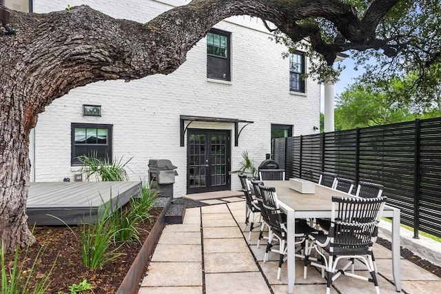 view of patio / terrace featuring grilling area, fence, a deck, outdoor dining area, and french doors