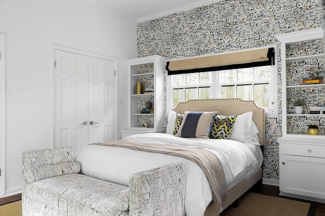 bedroom with ornamental molding, a closet, wood finished floors, and baseboards