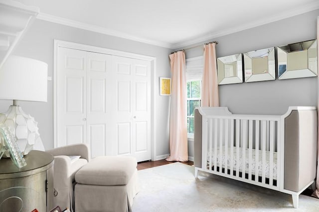 bedroom with a closet, ornamental molding, wood finished floors, a nursery area, and baseboards