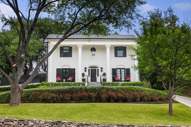 neoclassical / greek revival house featuring french doors, a front lawn, and stucco siding