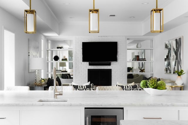 interior space with wine cooler, visible vents, a fireplace, and crown molding