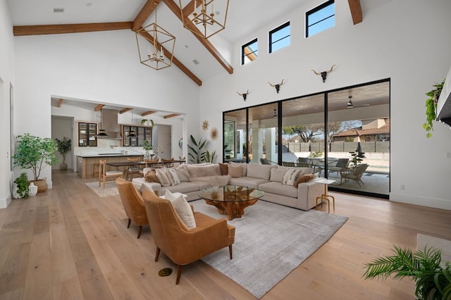 living area with light wood-style floors, beamed ceiling, a wealth of natural light, and a notable chandelier