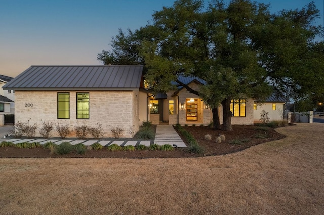 view of front of property featuring metal roof, stone siding, and a standing seam roof