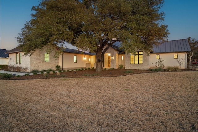 ranch-style home with a standing seam roof, a front lawn, and metal roof