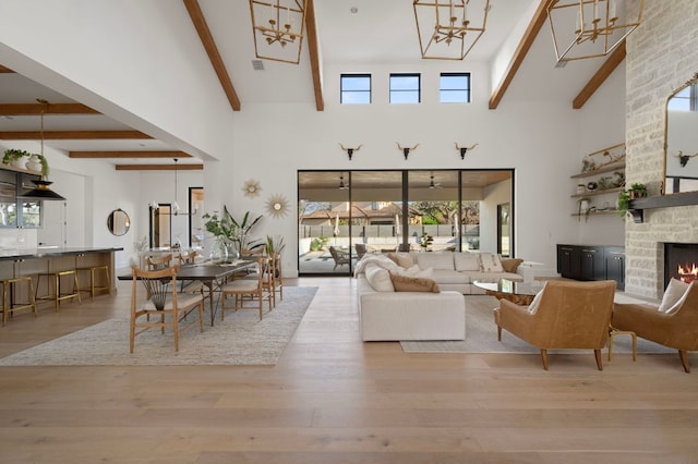 living room featuring beam ceiling, a stone fireplace, and wood finished floors