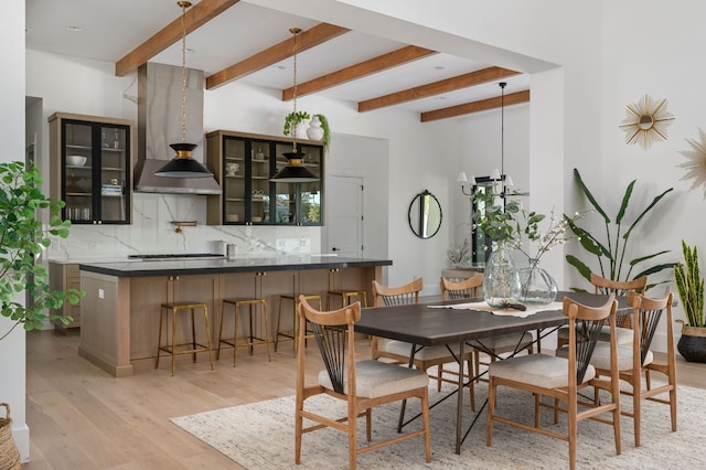 dining area featuring light wood-type flooring and beam ceiling