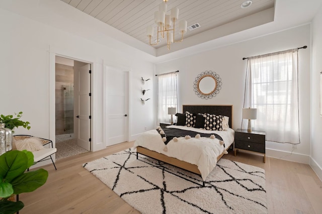 bedroom featuring wooden ceiling, light wood-style flooring, visible vents, baseboards, and a tray ceiling