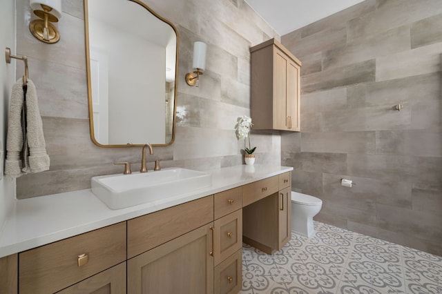 bathroom with toilet, tile patterned flooring, tile walls, and vanity