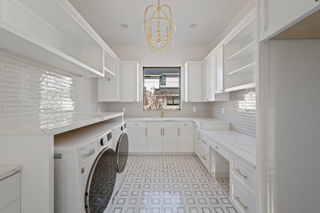 laundry room with a chandelier, washing machine and dryer, cabinet space, and a sink