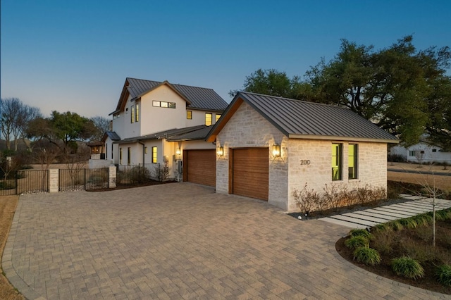 modern farmhouse style home featuring metal roof, decorative driveway, a standing seam roof, and an attached garage