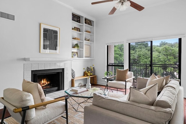 living area featuring wood finished floors, a tile fireplace, visible vents, and crown molding