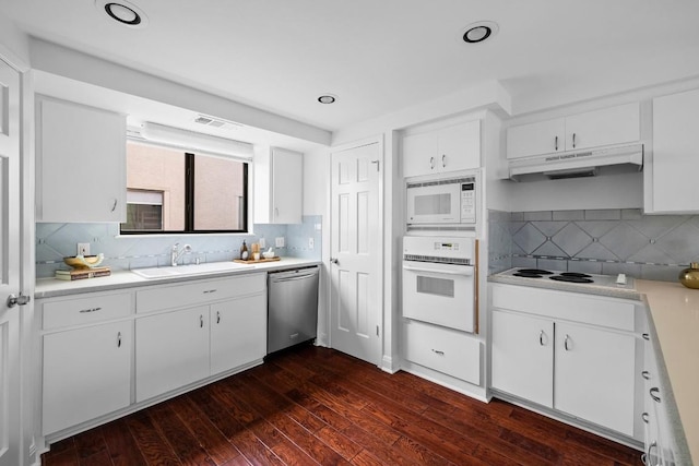 kitchen with under cabinet range hood, white appliances, a sink, light countertops, and dark wood-style floors