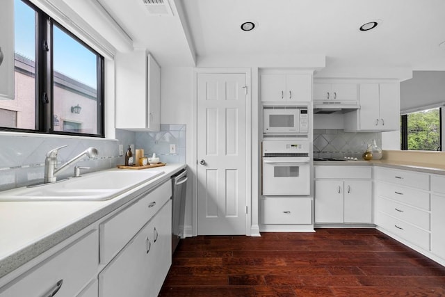 kitchen with white appliances, visible vents, light countertops, under cabinet range hood, and a sink