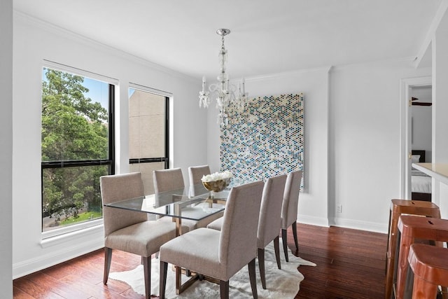 dining space featuring a healthy amount of sunlight, wood-type flooring, an inviting chandelier, and crown molding