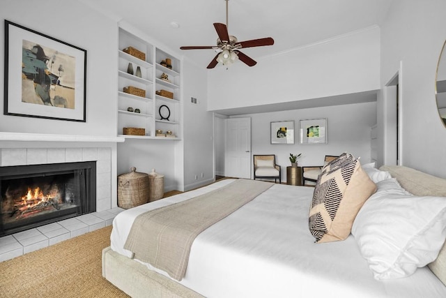 bedroom with crown molding, a ceiling fan, and a tiled fireplace