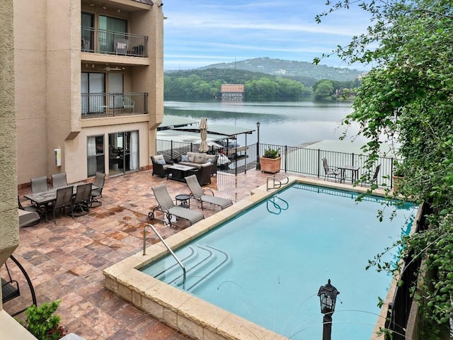 view of pool featuring a patio area, a water view, and outdoor lounge area