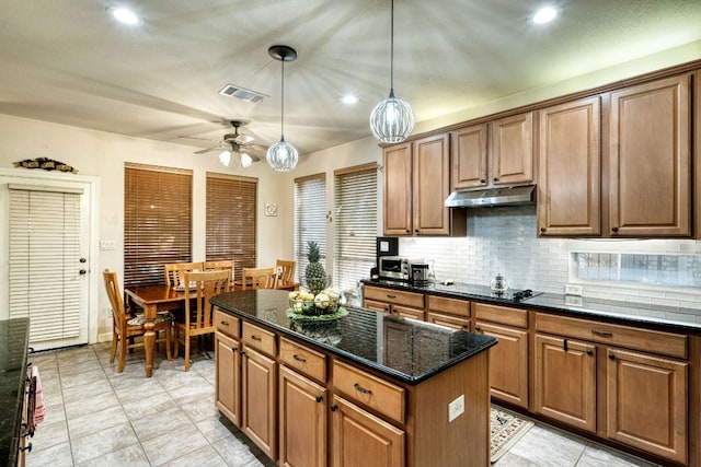 kitchen featuring visible vents, a kitchen island, black electric cooktop, under cabinet range hood, and backsplash