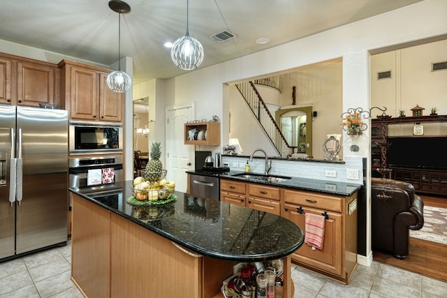 kitchen featuring dark stone counters, stainless steel appliances, a sink, and visible vents