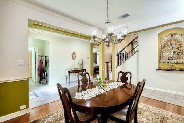 dining area with a notable chandelier, crown molding, visible vents, and wood finished floors