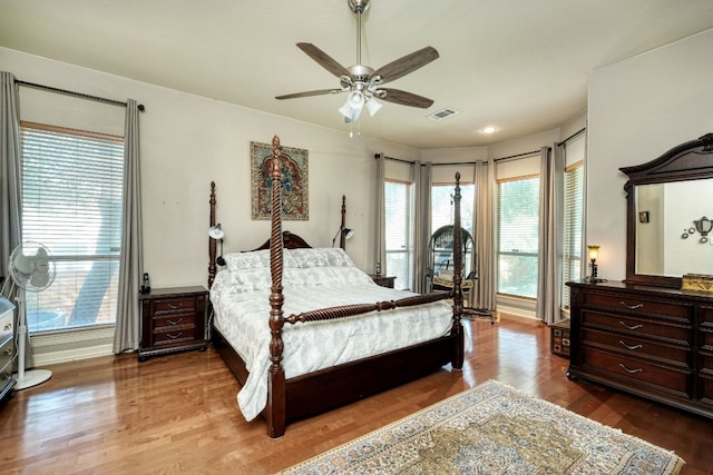 bedroom featuring a ceiling fan, visible vents, baseboards, and wood finished floors