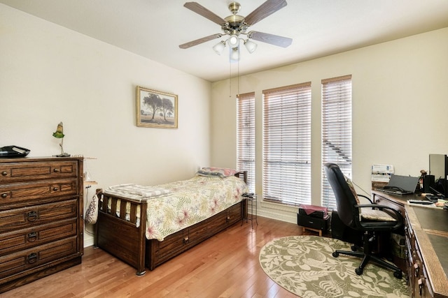 bedroom featuring ceiling fan, multiple windows, and light wood-style flooring