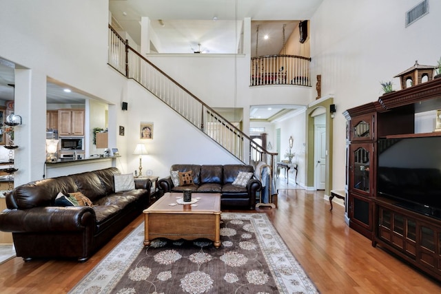 living room with a high ceiling, stairs, baseboards, and wood finished floors