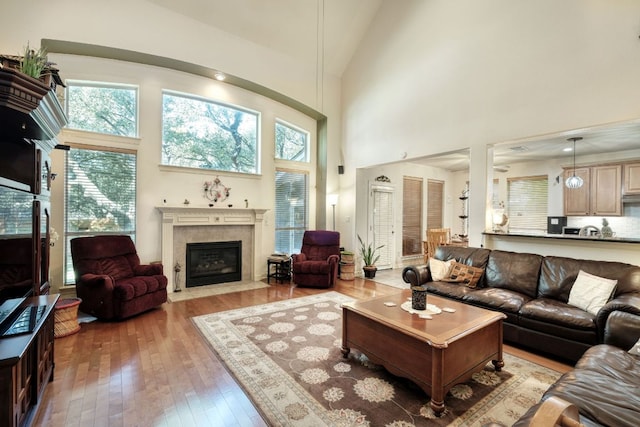 living area featuring high vaulted ceiling, hardwood / wood-style floors, and a tile fireplace