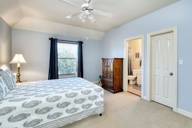 bedroom featuring lofted ceiling, ensuite bath, baseboards, and light colored carpet