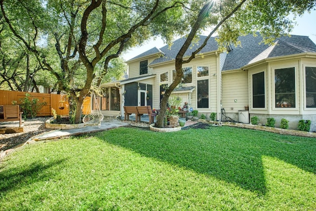 back of property with a shingled roof, a patio, a sunroom, fence, and a yard