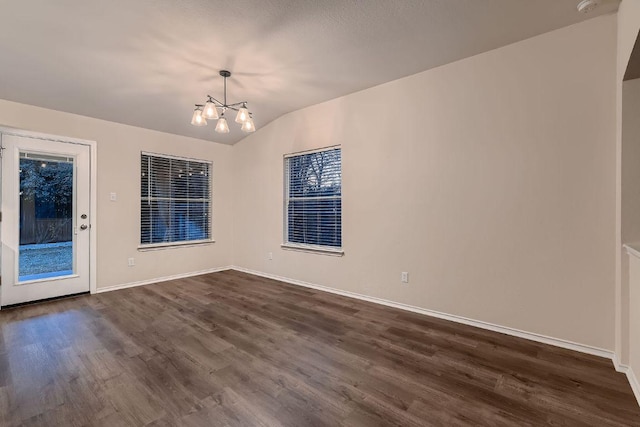 unfurnished room featuring dark wood-type flooring, a chandelier, vaulted ceiling, and baseboards