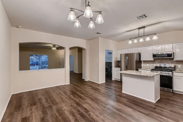 kitchen featuring arched walkways, stainless steel appliances, visible vents, and a center island