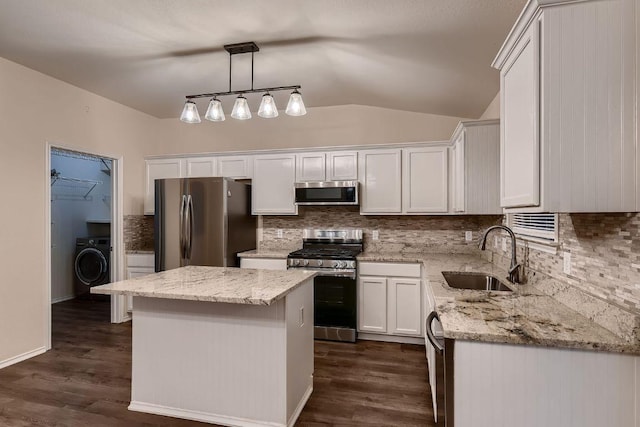 kitchen featuring washer / clothes dryer, a sink, stainless steel appliances, white cabinetry, and backsplash